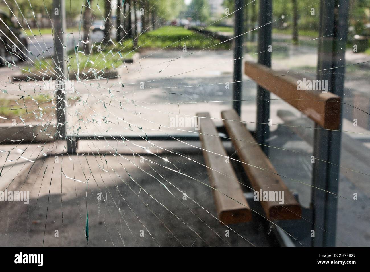 Die Bank befindet sich hinter dem zerbrochenen Glas der Bushaltestelle Stockfoto