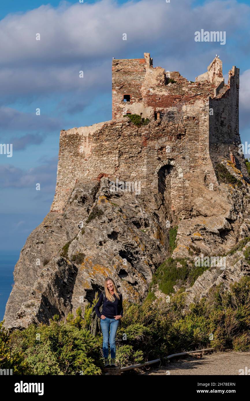 Eine blonde Frau mit dem Torre Vecchia Turm im Hintergrund, Gorgona Island, Italien Stockfoto