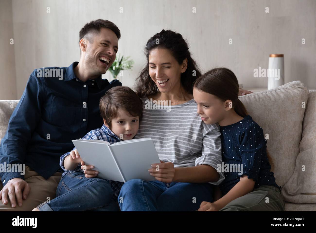 Fröhliche Familie mit Kindern sitzen auf dem Sofa und lesen ein Buch Stockfoto
