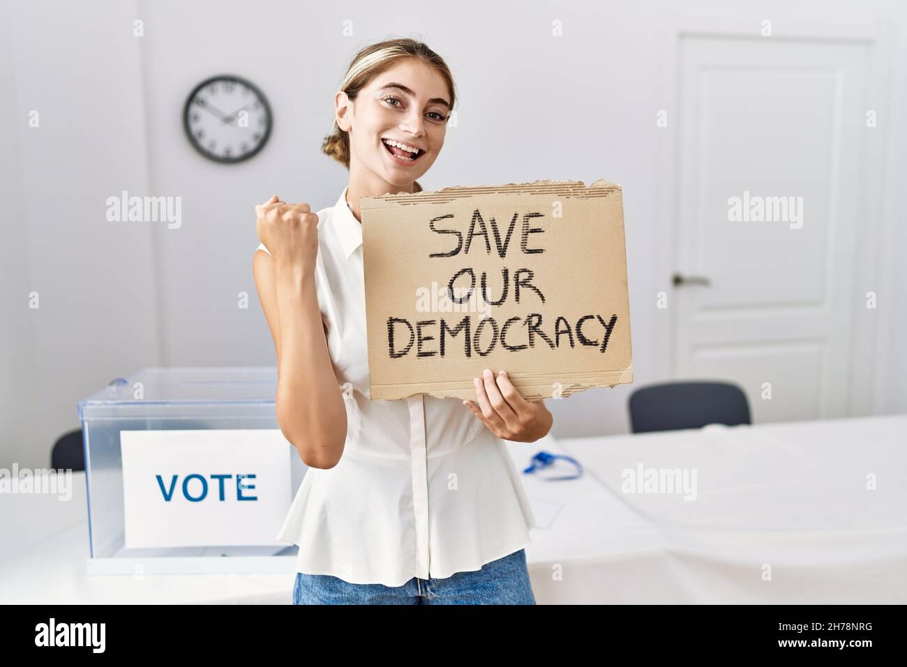 Junge blonde Frau bei den politischen Wahlen hält Save out Demokratie Banner schreiend stolz, feiert Sieg und Erfolg sehr aufgeregt mit angehoben ein Stockfoto