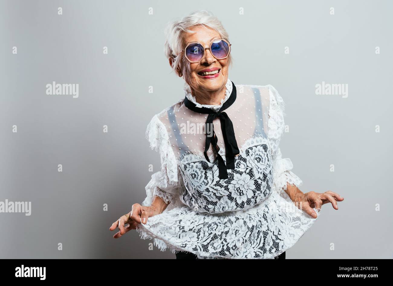 Schöne und elegante alte Influencer Frau. Coole Großmutter posiert im Studio und trägt modische Kleidung. Glückliche ältere Dame feiern und pa machen Stockfoto