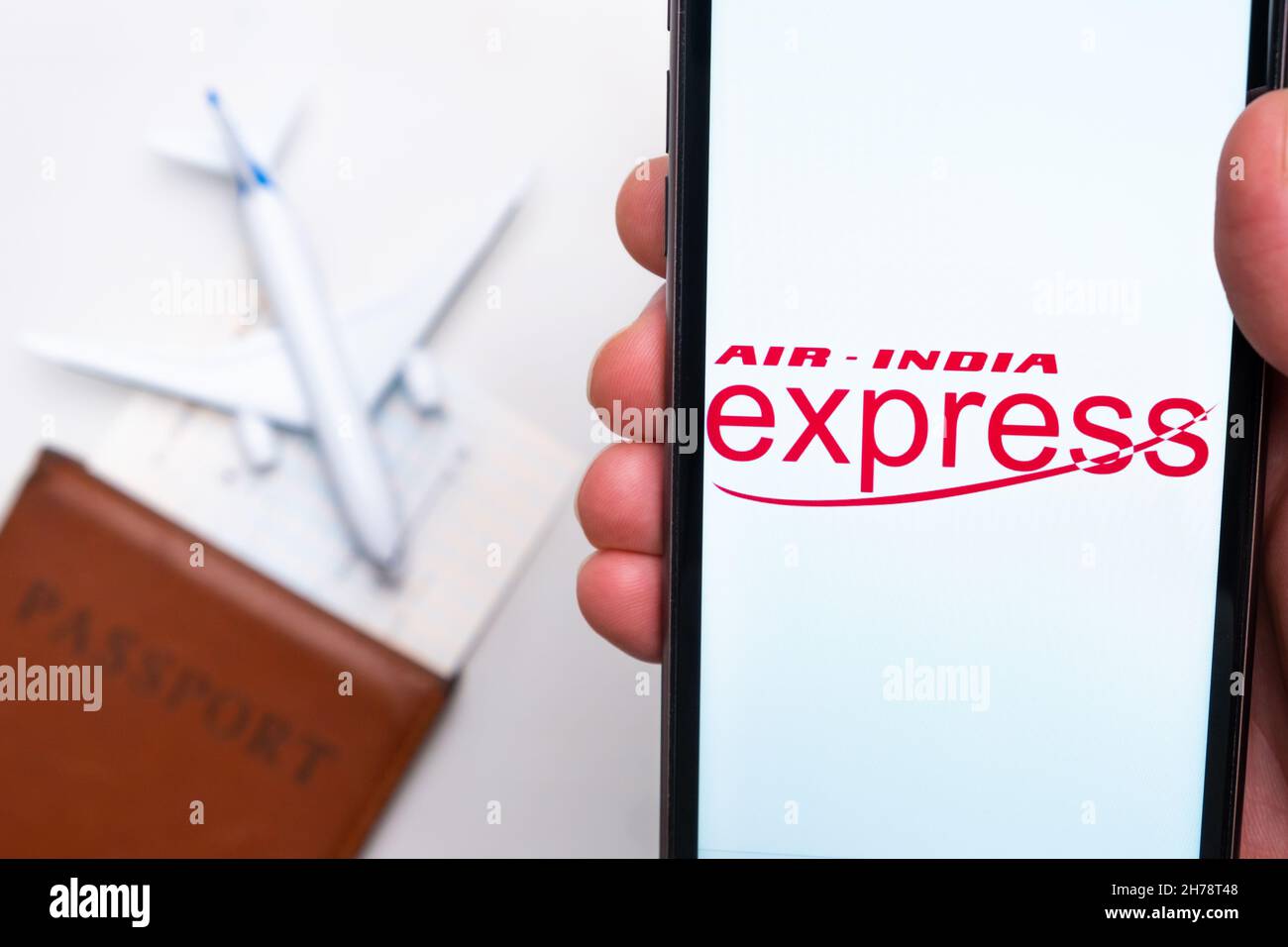 Air India Express Airline-App auf einem Smartphone-Bildschirm in Mans-Hand. Ein Spielzeugflugzeug, Reisepass und Tickets stehen auf dem Tisch. November 2021, San Francisco, USA Stockfoto