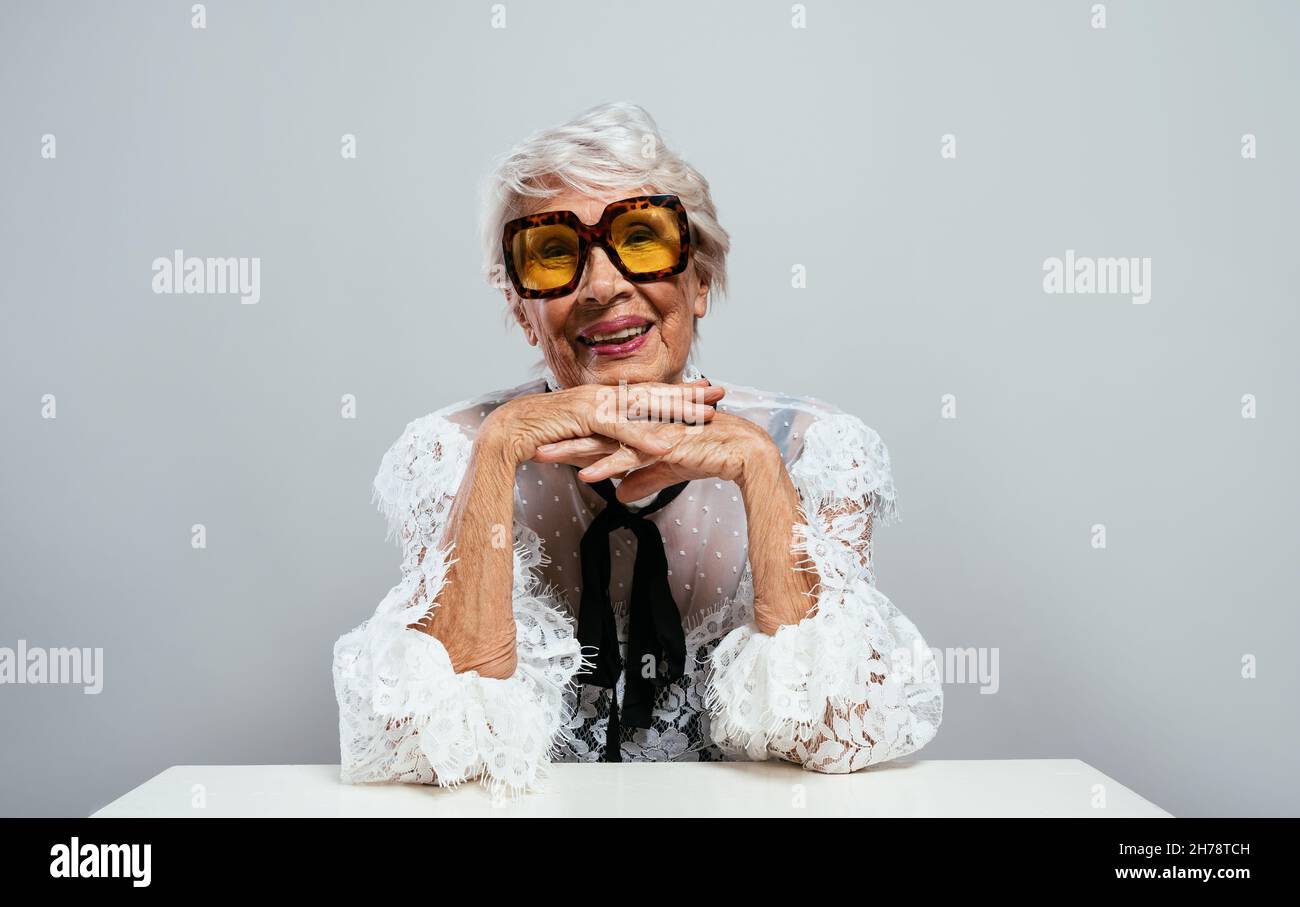 Schöne und elegante alte Influencer Frau. Coole Großmutter posiert im Studio und trägt modische Kleidung. Glückliche ältere Dame feiern und pa machen Stockfoto