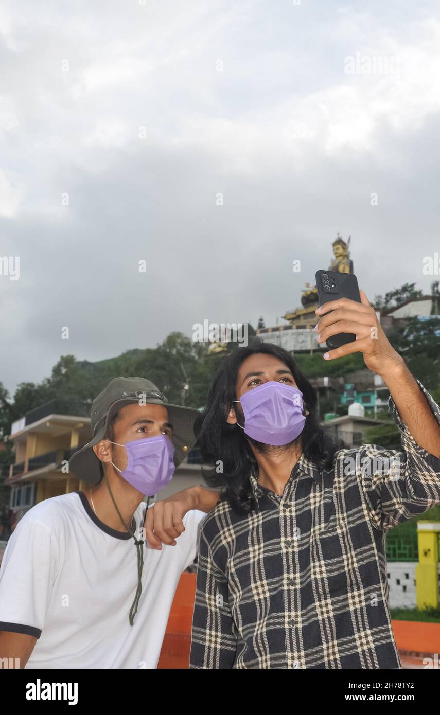 Zwei männliche Freunde mit Gesichtsmaske, die während der Covid-19-Pandemie zusammen Selfie im Freien machen Stockfoto