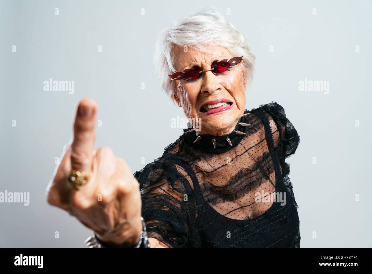 Schöne und elegante alte Influencer Frau. Coole Großmutter posiert im Studio und trägt modische Kleidung. Glückliche ältere Dame feiern und pa machen Stockfoto