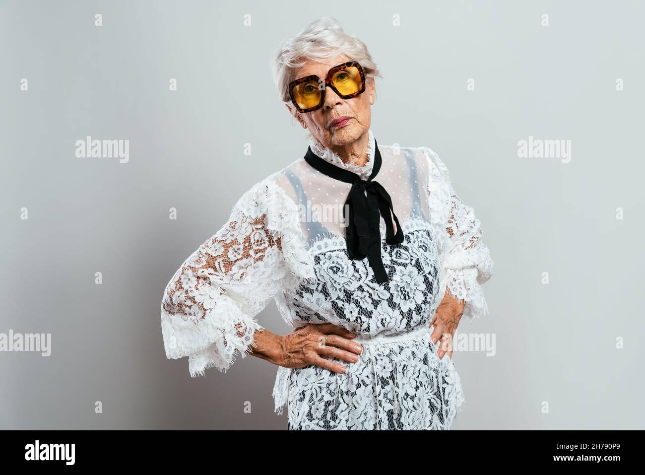 Schöne und elegante alte Influencer Frau. Coole Großmutter posiert im Studio und trägt modische Kleidung. Glückliche ältere Dame feiern und pa machen Stockfoto