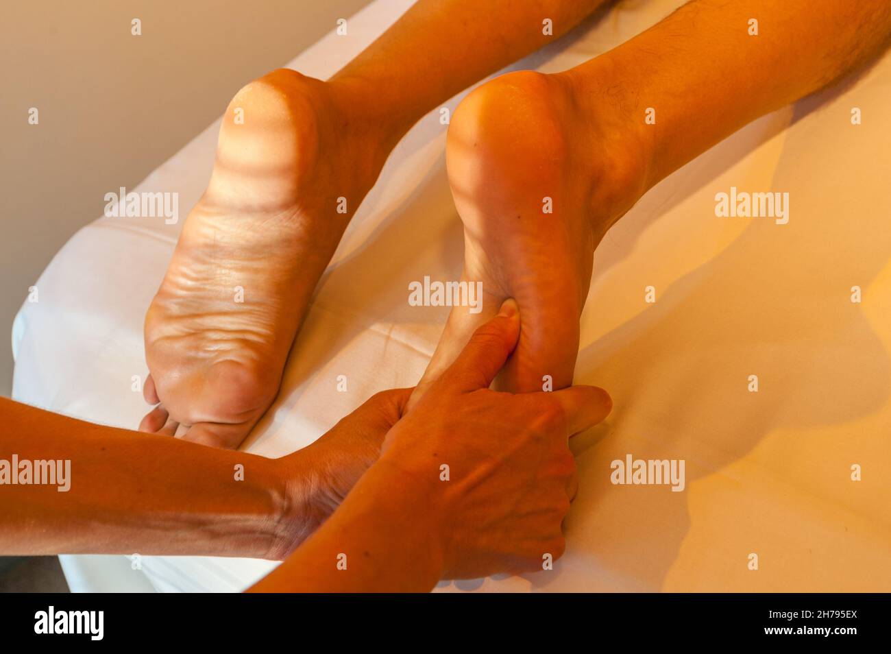 Fußsohlenmassage, masseuse Hände massieren Männerfuß Stockfoto