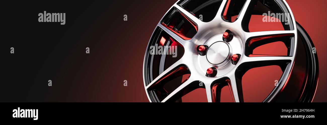 Das neue Leichtmetallrad ist leicht und sportlich rot mit glänzenden Speichen auf einem rot-schwarzen Hintergrund, schönen roten Muttern Radbefestigungen. Copys Stockfoto