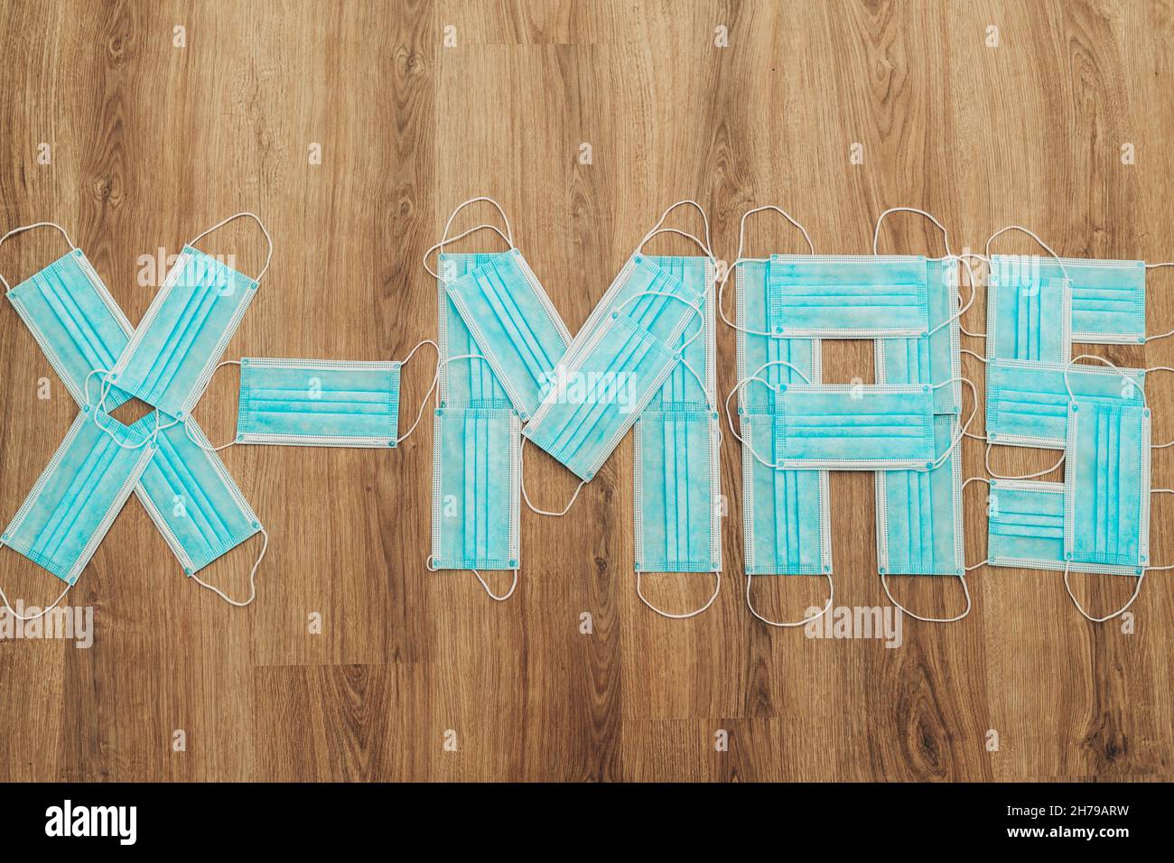 Word X-Mas aus medizinischen Masken auf einem braunen Hintergrund Mit Kopierbereich Stockfoto