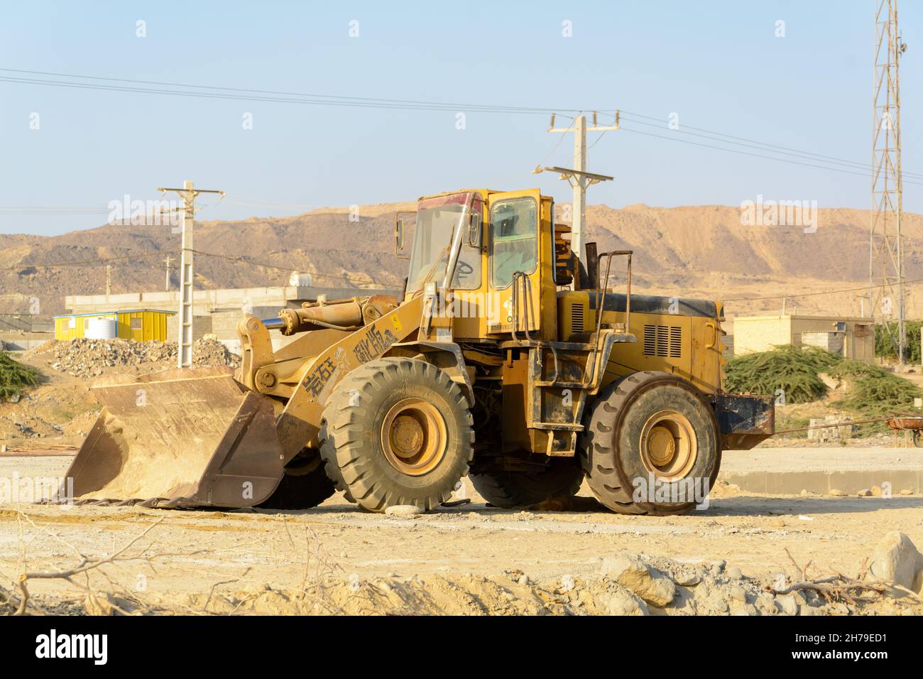 chabahar, iran 27 october 2021, großer gelber Frontlader oder Allrad-Bulldozer, Seitenansicht vom gelben rostigen Lader, der mit geöffneter Tür geparkt ist Stockfoto
