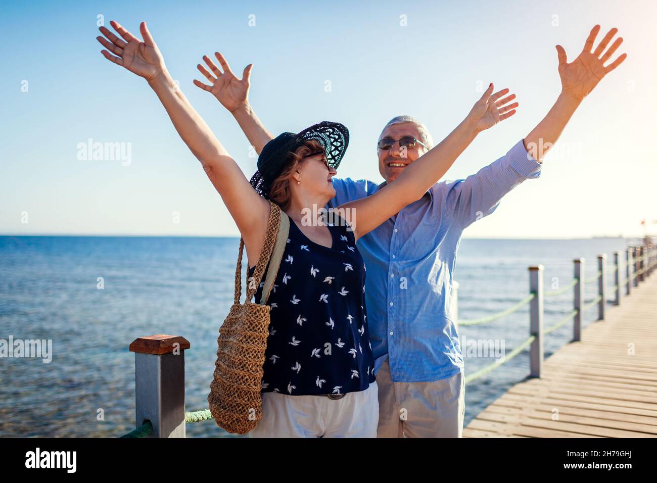 Ein älteres Familienpaar, das am Pier am Roten Meer die Arme hochhebt. Glückliche Rentner, die Urlaub in Sharm el Sheikh in Ägypten feiern. Stockfoto Ein älteres Familienpaar, das am Pier am Roten Meer die Arme hochhebt. Glückliche Rentner, die Urlaub in Sharm el Sheikh in Ägypten feiern. Stockfoto