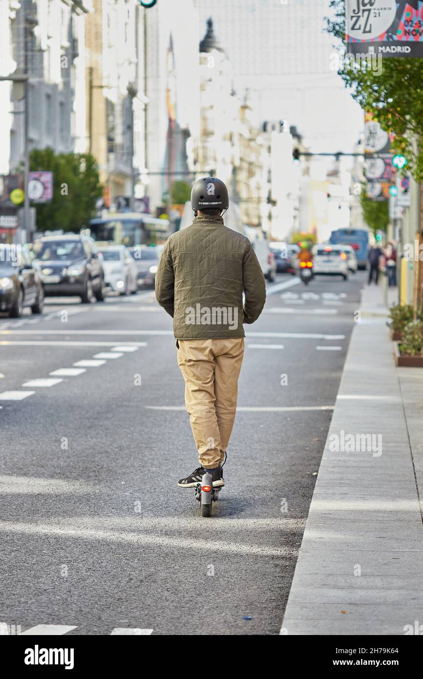 Junger Mann, der einen Elektroroller in Gran Vía (Madrid, Spanien) fährt. Stockfoto