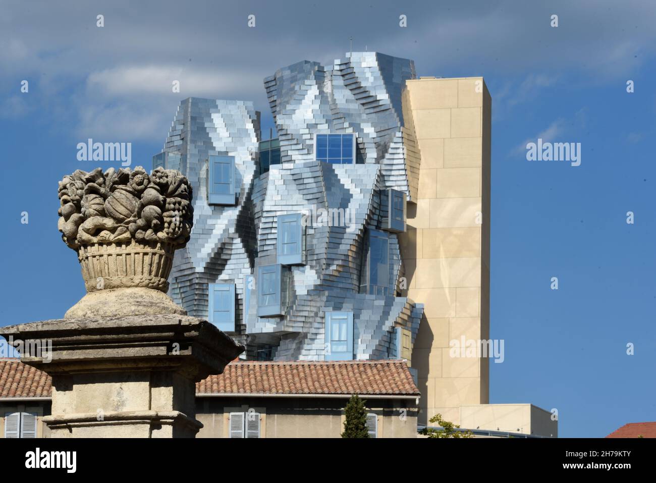 Der von Frank Gehry entworfene Turm der Stiftung Luma überragt die traditionelle Architektur und die Pfostenstatuar des Obstkorbes in Arles Provence Frankreich Stockfoto