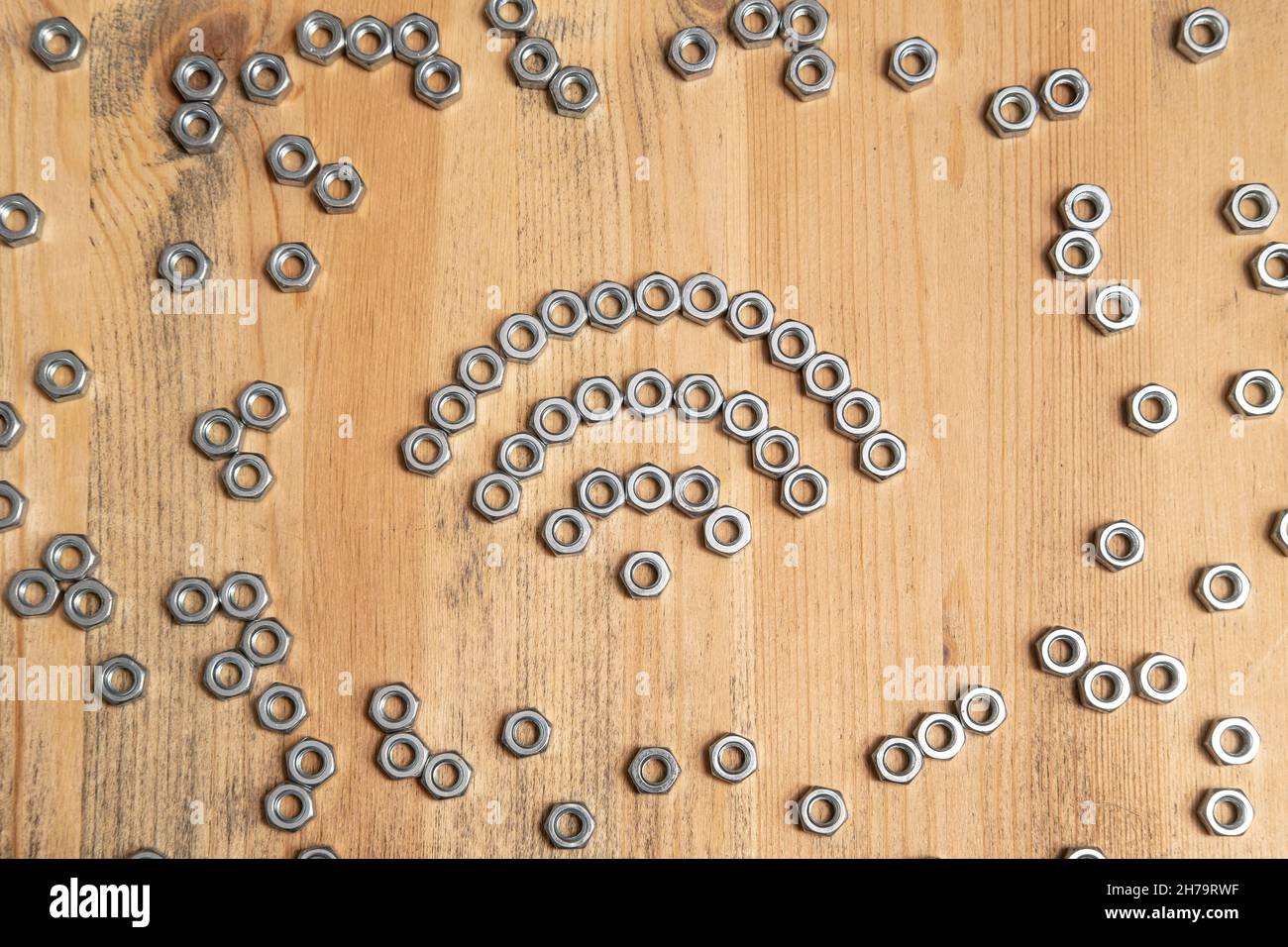 WiFi-Schild aus Metallmuttern auf einem Holztisch. Draufsicht. Stockfoto