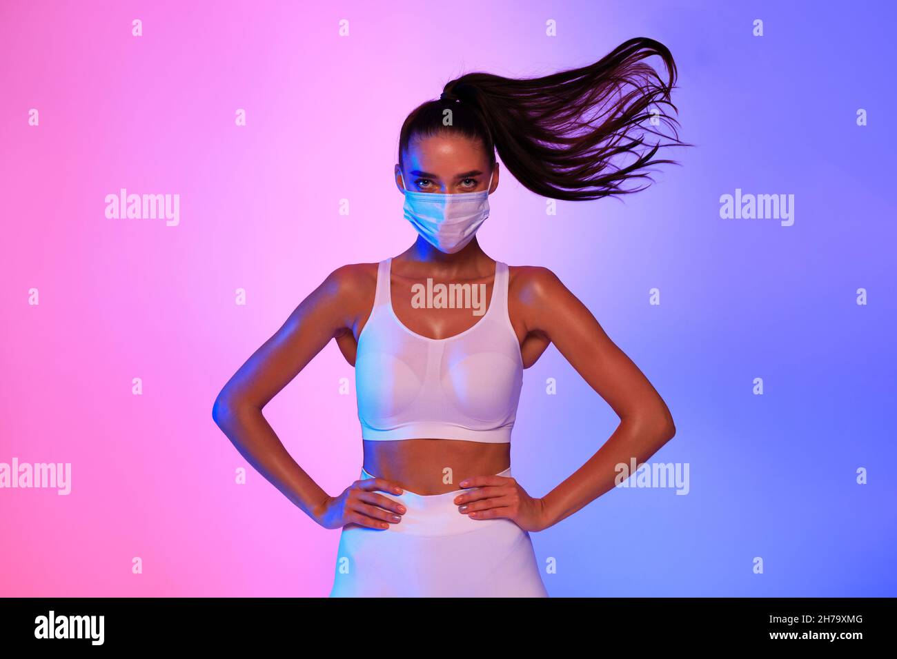 Fitness Weibliche Tragen Gesichtsmaske Posiert Mit Fliegenden Haaren, Studio Stockfoto
