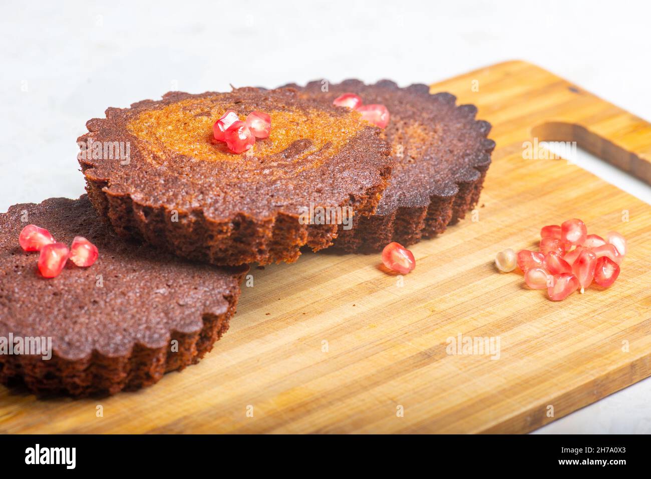 Drei kleine Kakaokuchen mit Granatapfel stehen auf dem Tisch Stockfoto