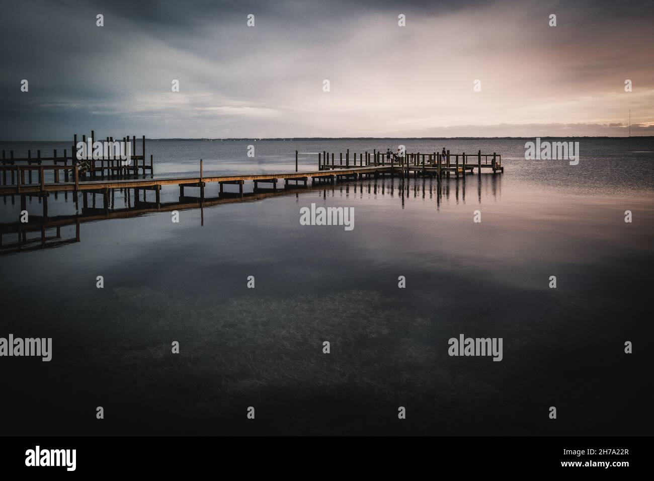 Ein filmisch stilisiertes Foto eines Piers, der am Abend beim Lichtverfall in den Currituck Sound ragt. Stockfoto