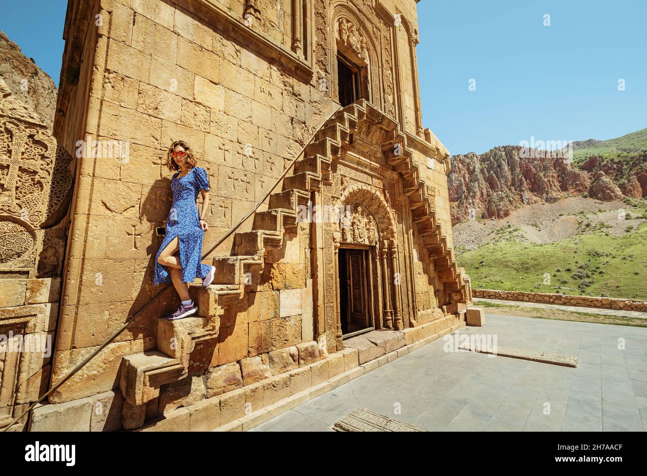 Glückliche Frau steigt die schmale Treppe in den zweiten Stock des Klosters Noravank. Reisen und Tourismus in Armenien Konzept Stockfoto