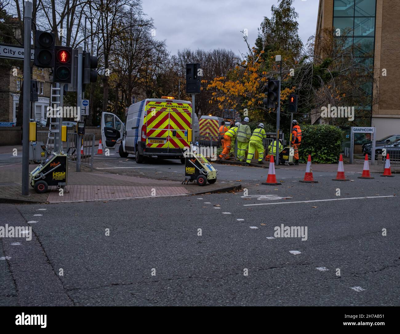Eine Gruppe von Arbeitern in Hi-viz-Kleidung und Hardhats grub den Straßenbelag aus und reparierte die Autobahn in der Stadt Cambridge, November 2021 Stockfoto
