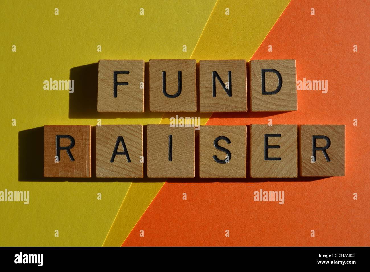 Fund Raiser, Wörter in Holzbuchstaben isoliert auf hellgelben und orangen Hintergrund Stockfoto