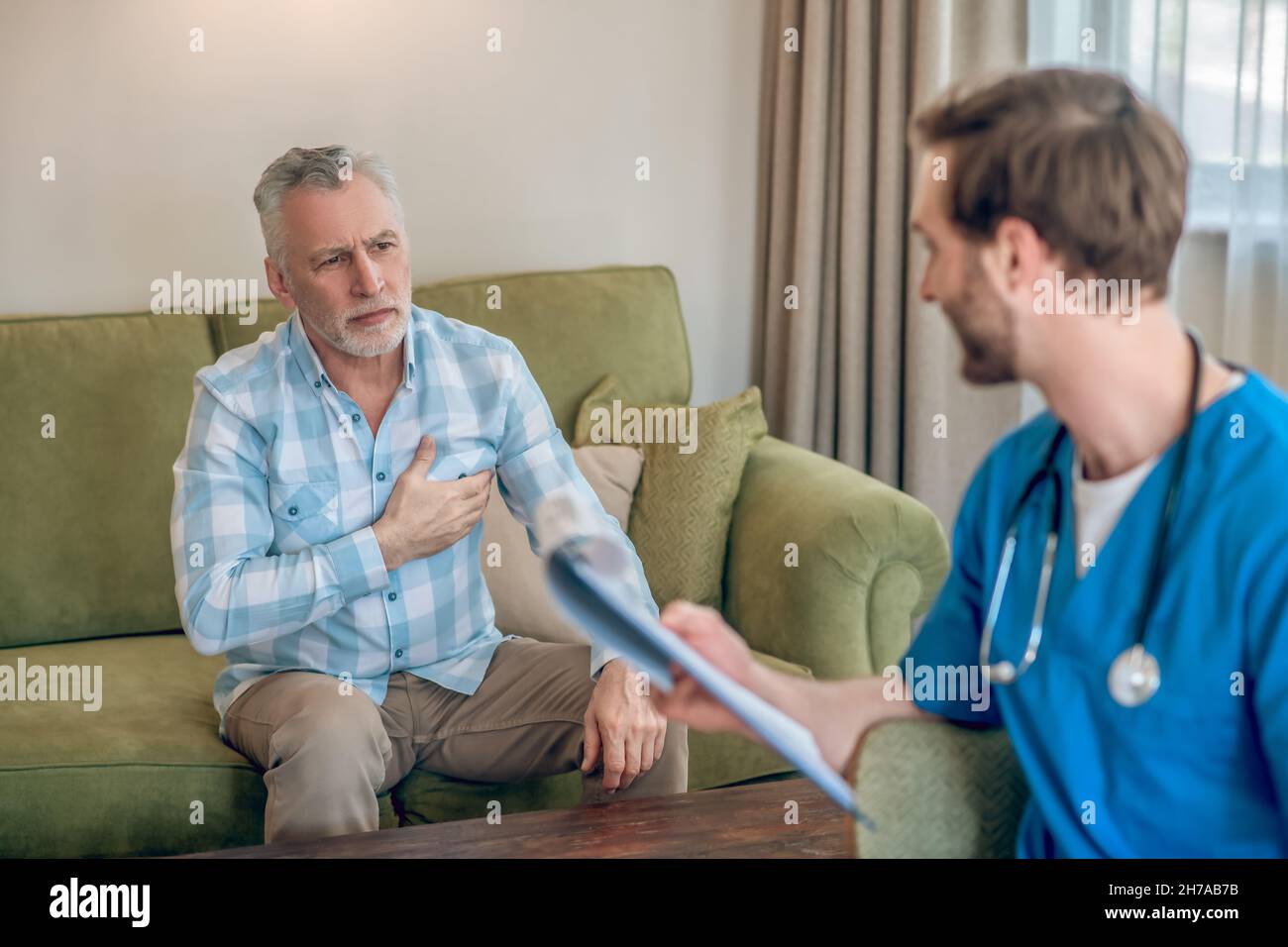 Männlicher Patient diskutiert sein Herzproblem mit einem Arzt Stockfoto