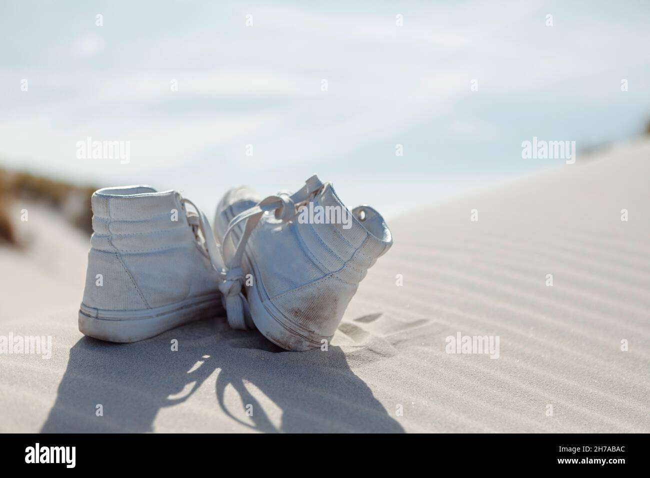 Rückansicht der Knöchelschuhe Paar auf Sand. Selektiver Fokus. Sommerurlaub, Urlaub am Meer Konzept. Stockfoto
