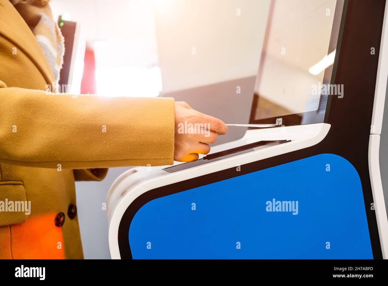 Die Passagierin scannt den Reisepass am Self-Service-Kiosk, um sich für den Flug einzuchecken, und vermeidet eine lange Warteschlange im internationalen Flughafenterminal in der Nähe Stockfoto