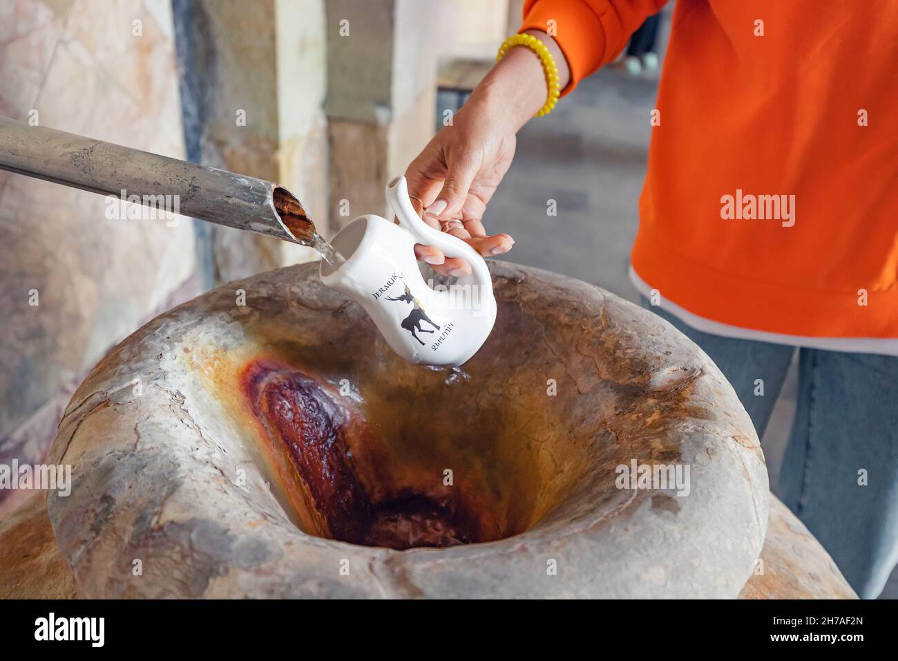 Eine Frau sammelt heisses Mineralwasser in der berühmten Heilquelle im Ferienort Jermuk in Armenien Stockfoto