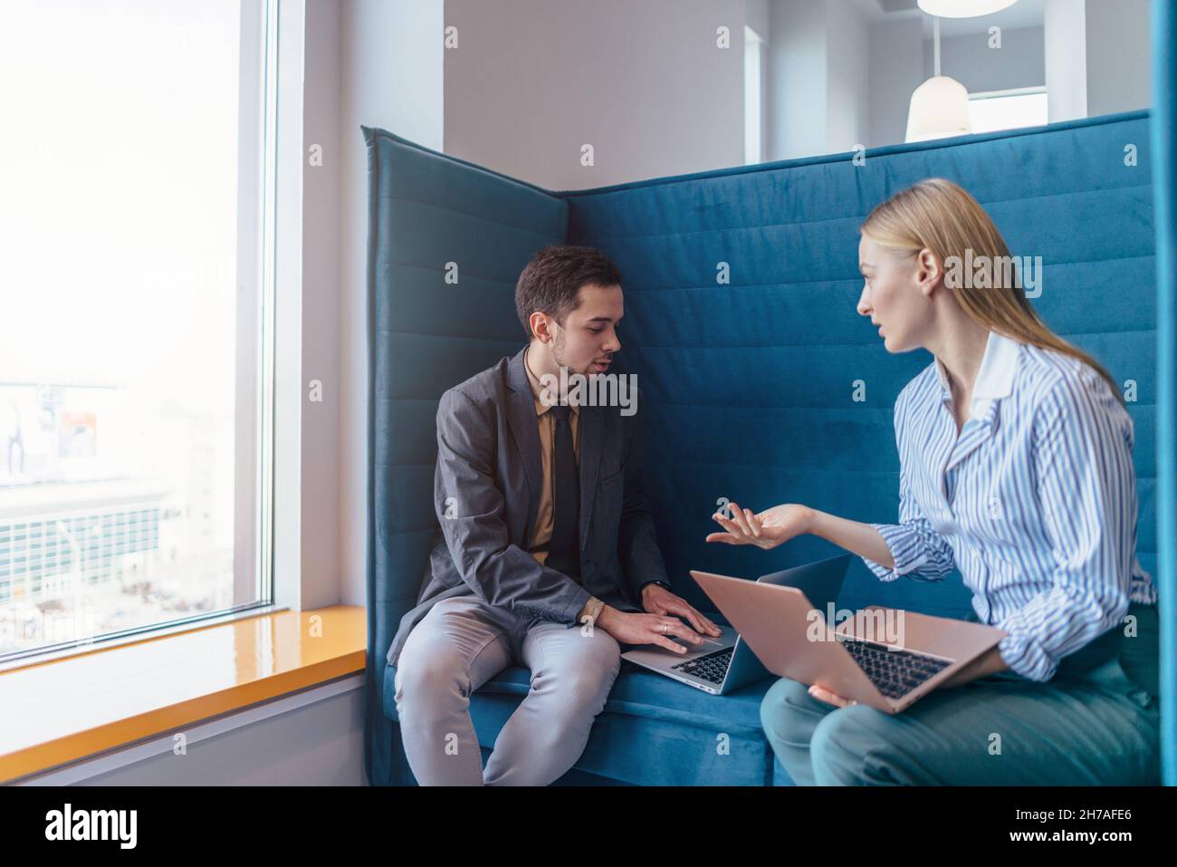 Frau und Mann sitzen mit ihren Laptops und führen informelle Geschäftsgespräche. Stockfoto