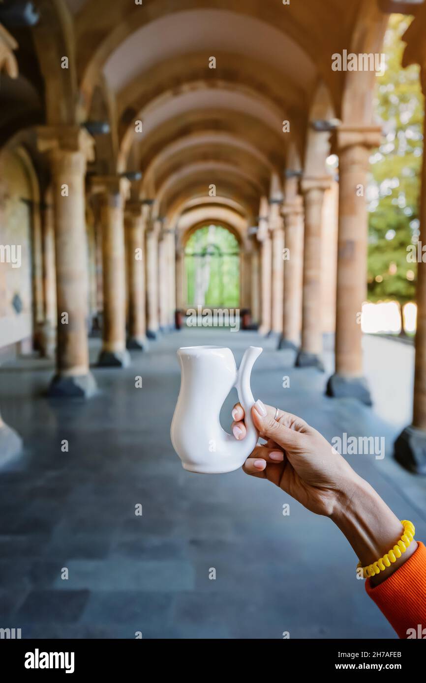 Becher zum Trinken von heißem mineralischem Heilwasser auf dem Hintergrund einer Galerie mit Säulen. Ein Resort für die Behandlung von Magen-Darm-Erkrankungen und Stockfoto