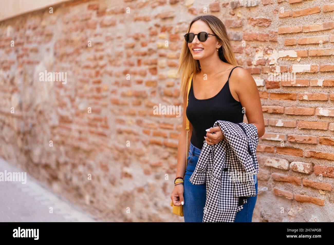 Trendige Frau in der Nähe einer Ziegelmauer auf der Straße Stockfoto