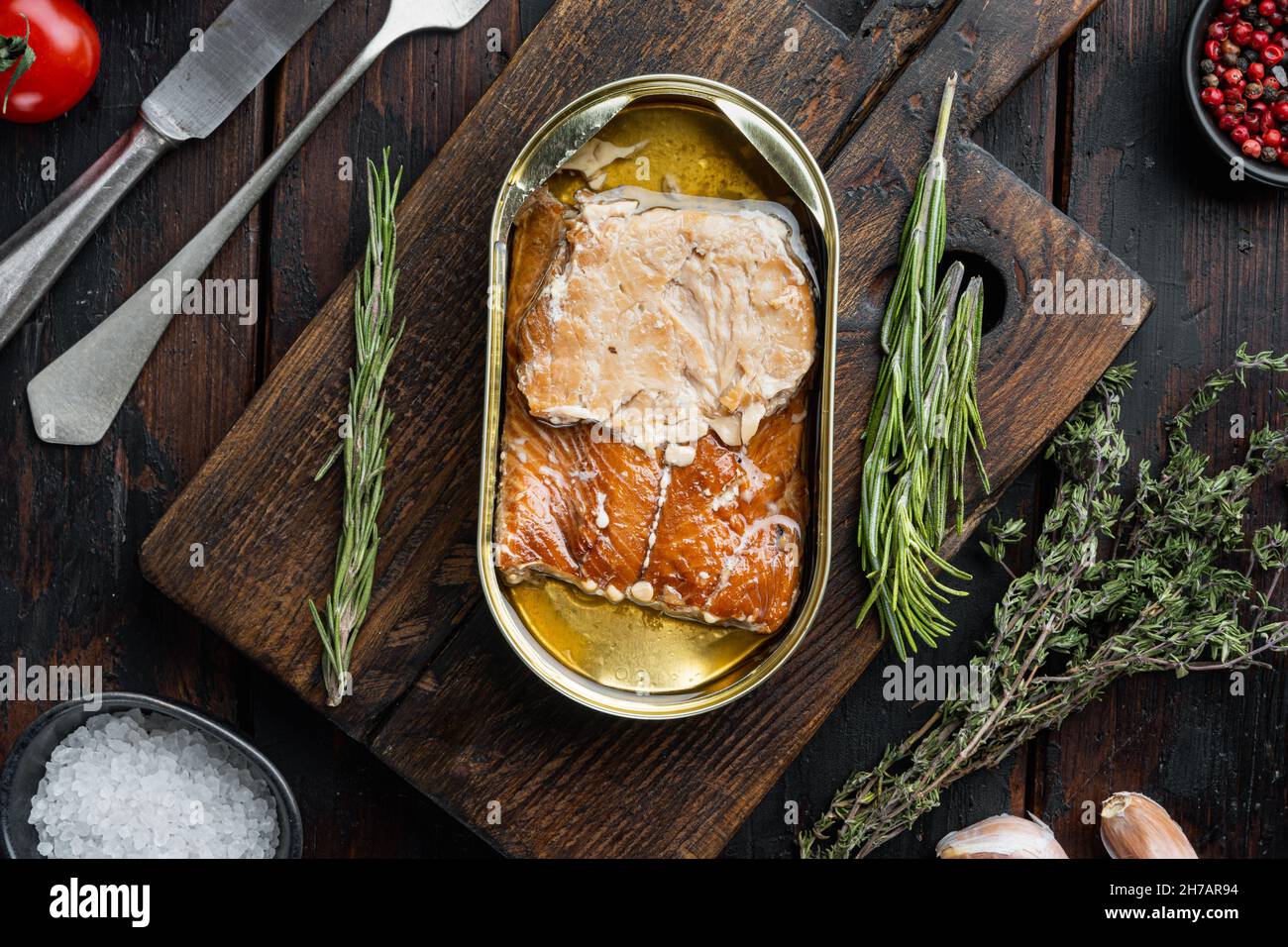 Wild Pink Salmon Räucherfischset in Dosen, auf Holzschneidebrett, auf altem dunklen Holztisch mit Kräutern und Zutaten, Draufsicht flach Stockfoto