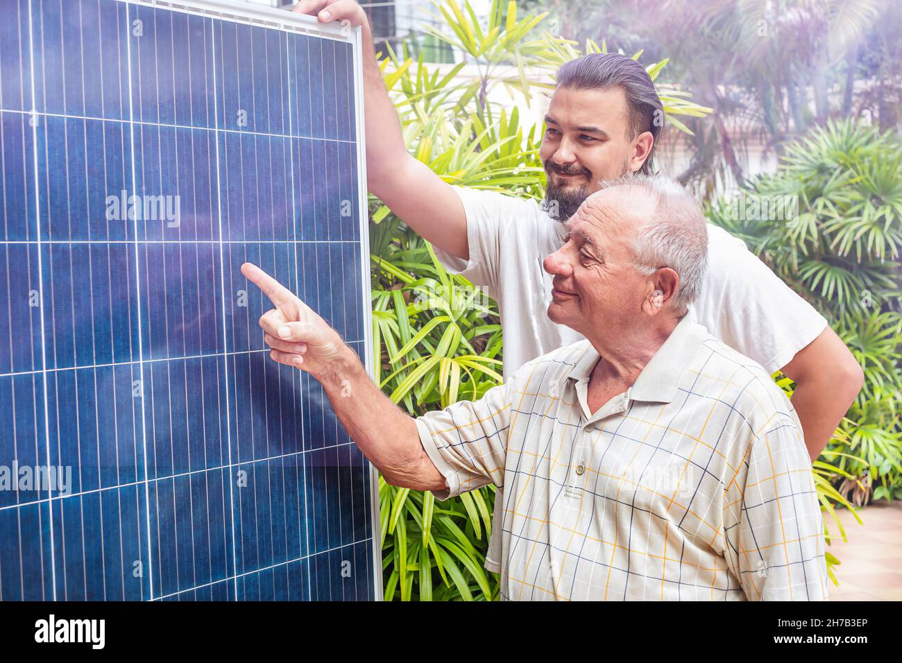 Der Mann zeigt dem Senioren die Solarzellen. Enkel spricht über Energie Stockfoto