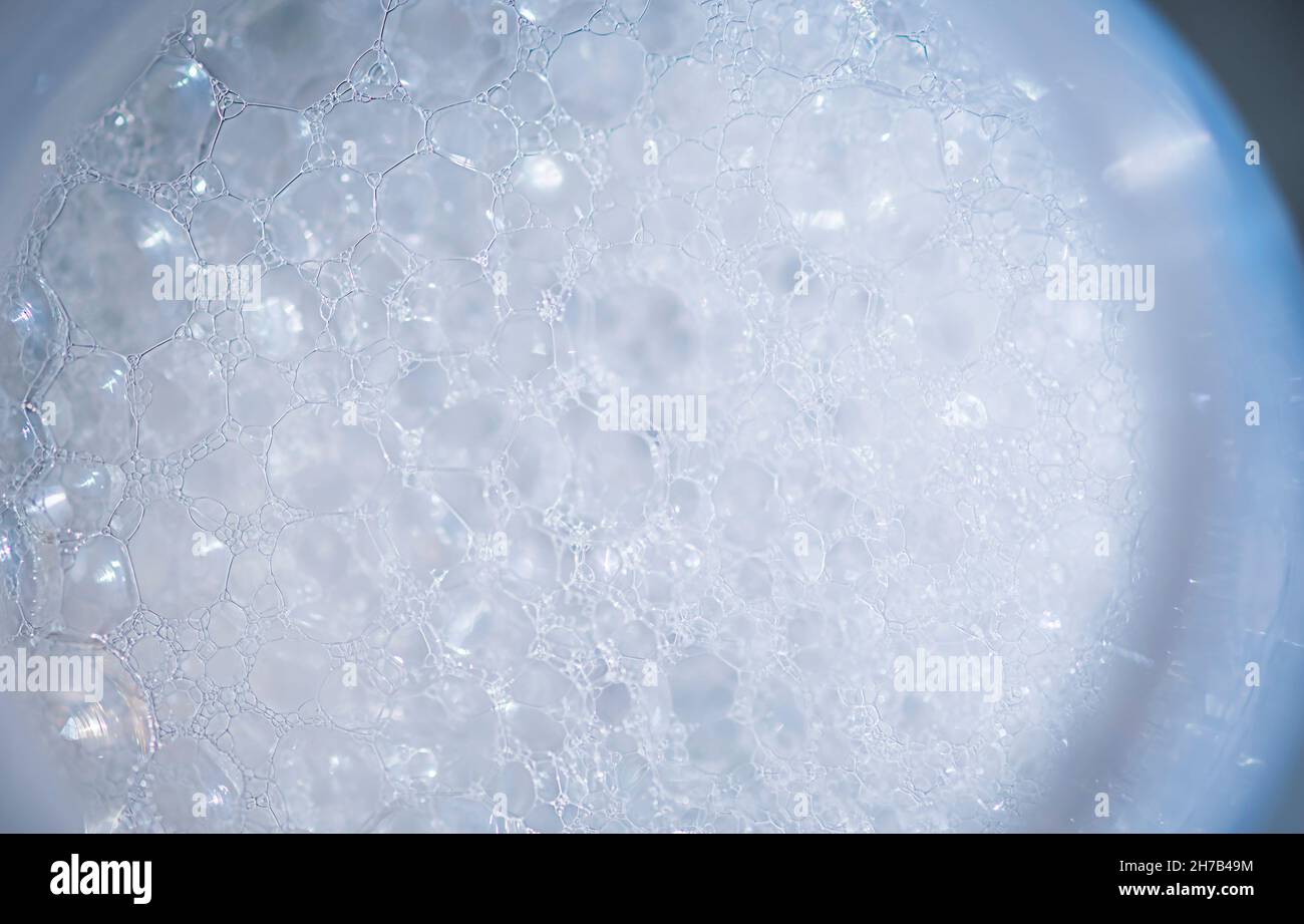 Weiße Schaumstoff-Textur mit Blasen. Weiche Blasen Hintergrund auf dem Glas Stockfoto