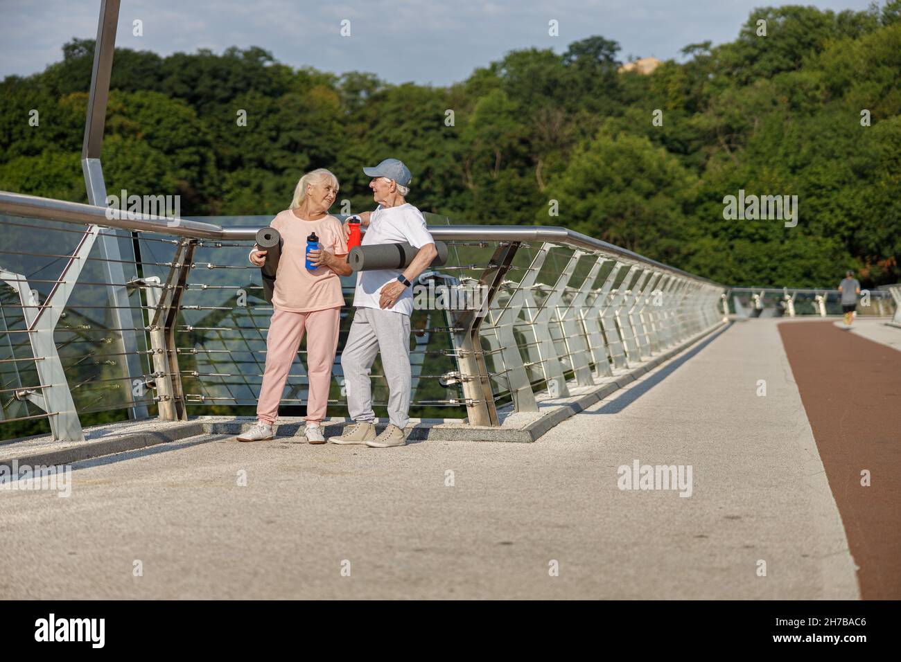 Ältere Frau und Mann mit Matten und Flaschen stehen auf dem Steg Stockfoto