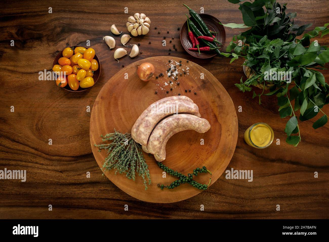 Traditionelle frische hausgemachte englische rohe Schweinefleischwürste auf rustikalem Holztisch mit natürlichen Zutaten Stockfoto