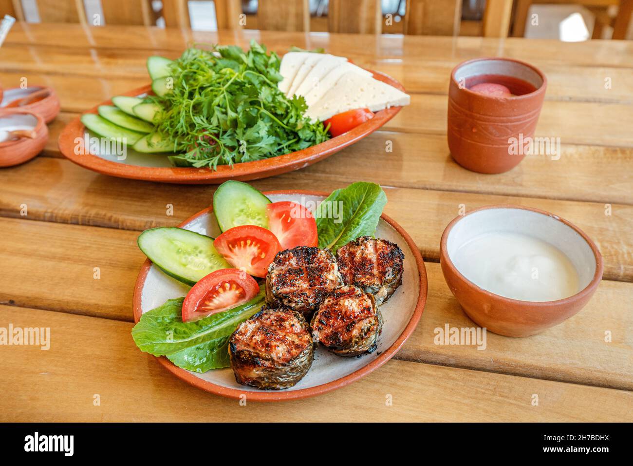 Armenisches herzhaftes Mittagessen. Auf dem Tisch steht ein Dolma aus Schischkebab mit Gemüse und Matsoni-Sauce. Traditionelle Küche Stockfoto