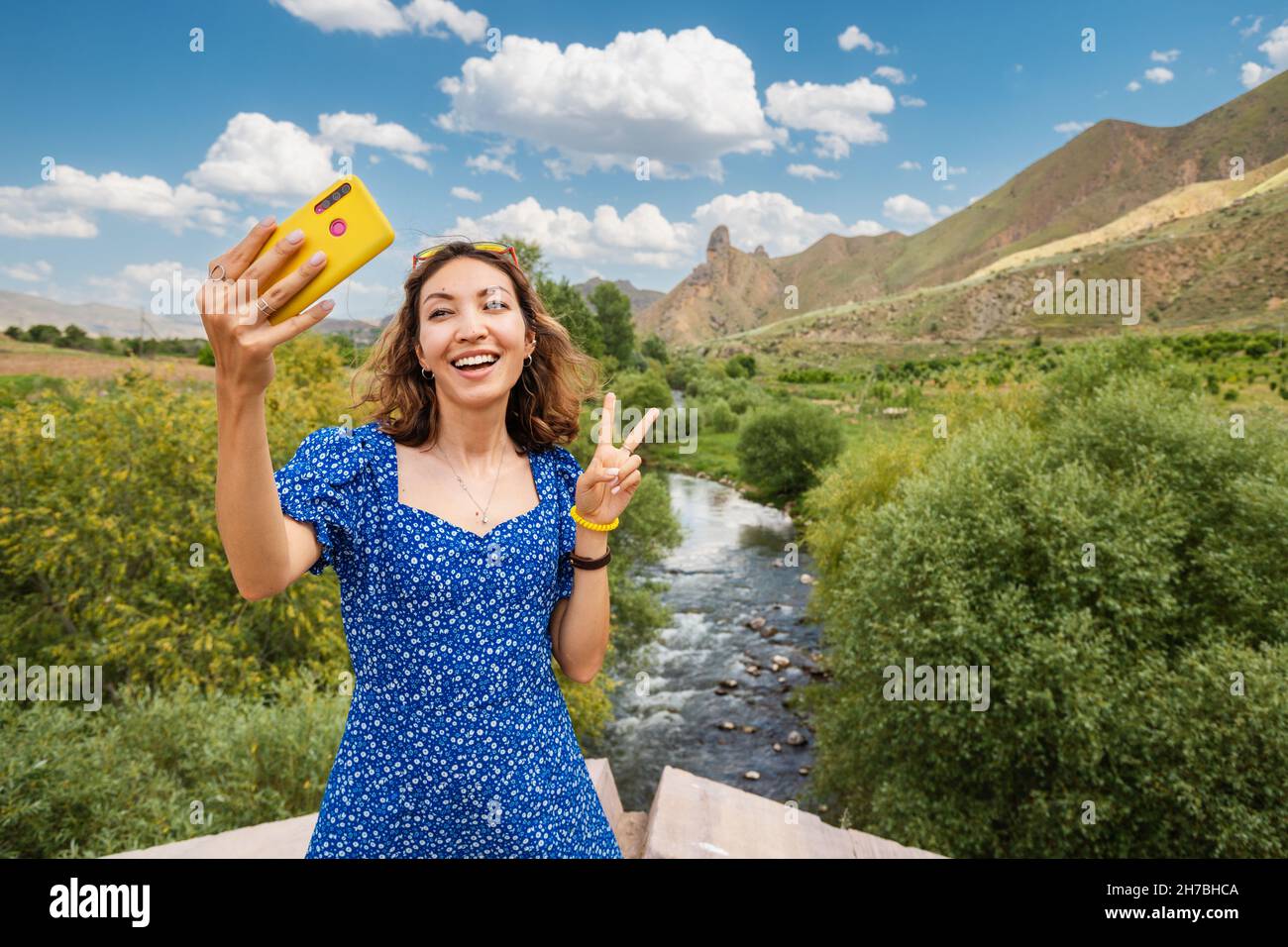 Touristenfrau am Aussichtspunkt, die Selfie-Fotos auf ihrem Smartphone am Hintergrund des Flusses und der Moiuntains machte. Reisen und Tourismus in Armenien Stockfoto