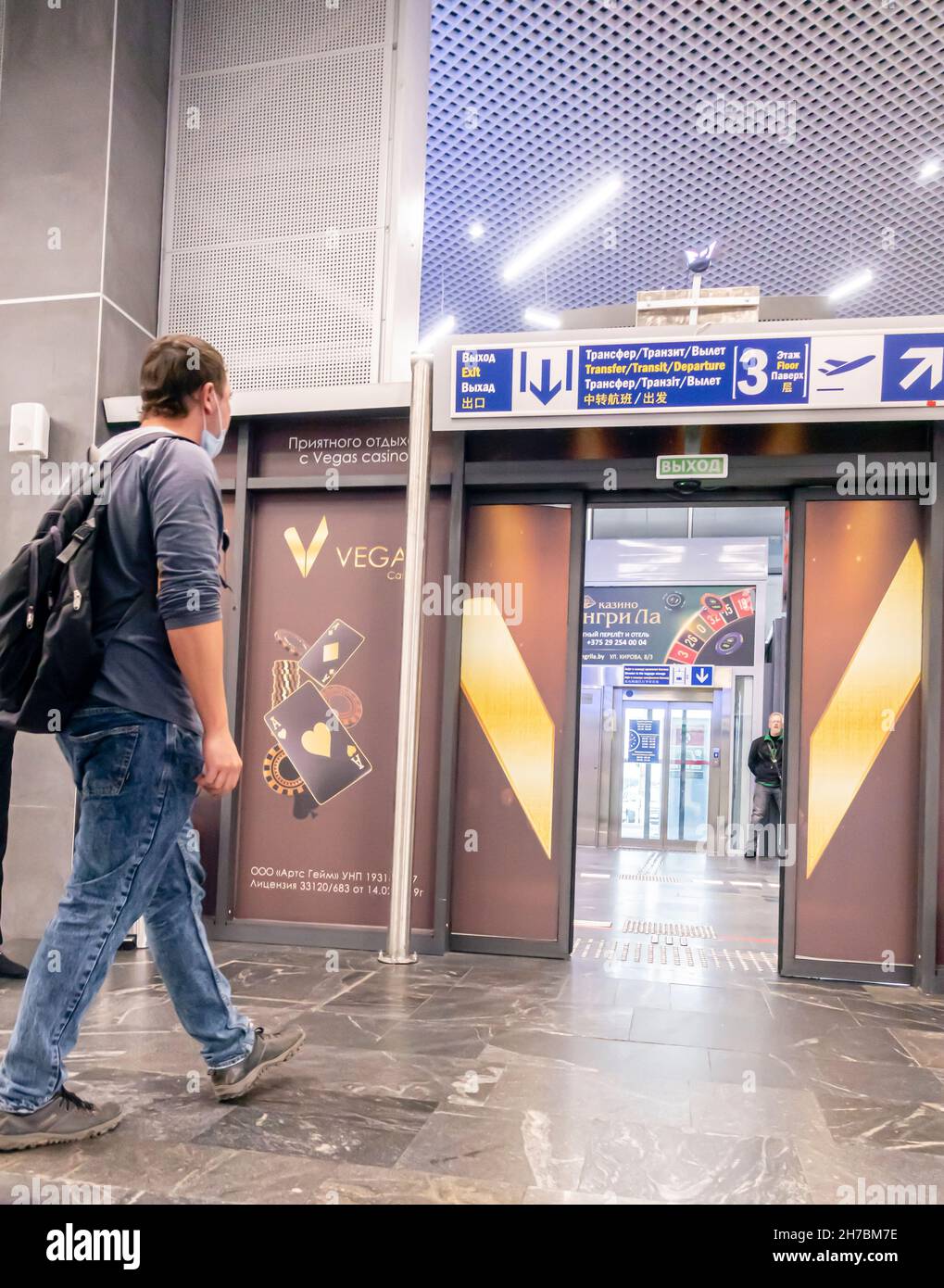 Ein männlicher Passagier mit einer Gesichtsmaske am Kinn, der nach der Landung auf dem Nationalflughafen Minsk, Weißrussland, in Richtung eines Transfer-Gates ging Stockfoto