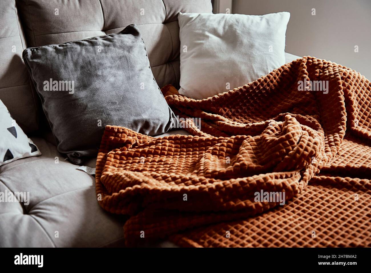 Leere Couch mit Plaid und Kissen. Ort zum Entspannen, gemütliches Zuhause Stockfoto