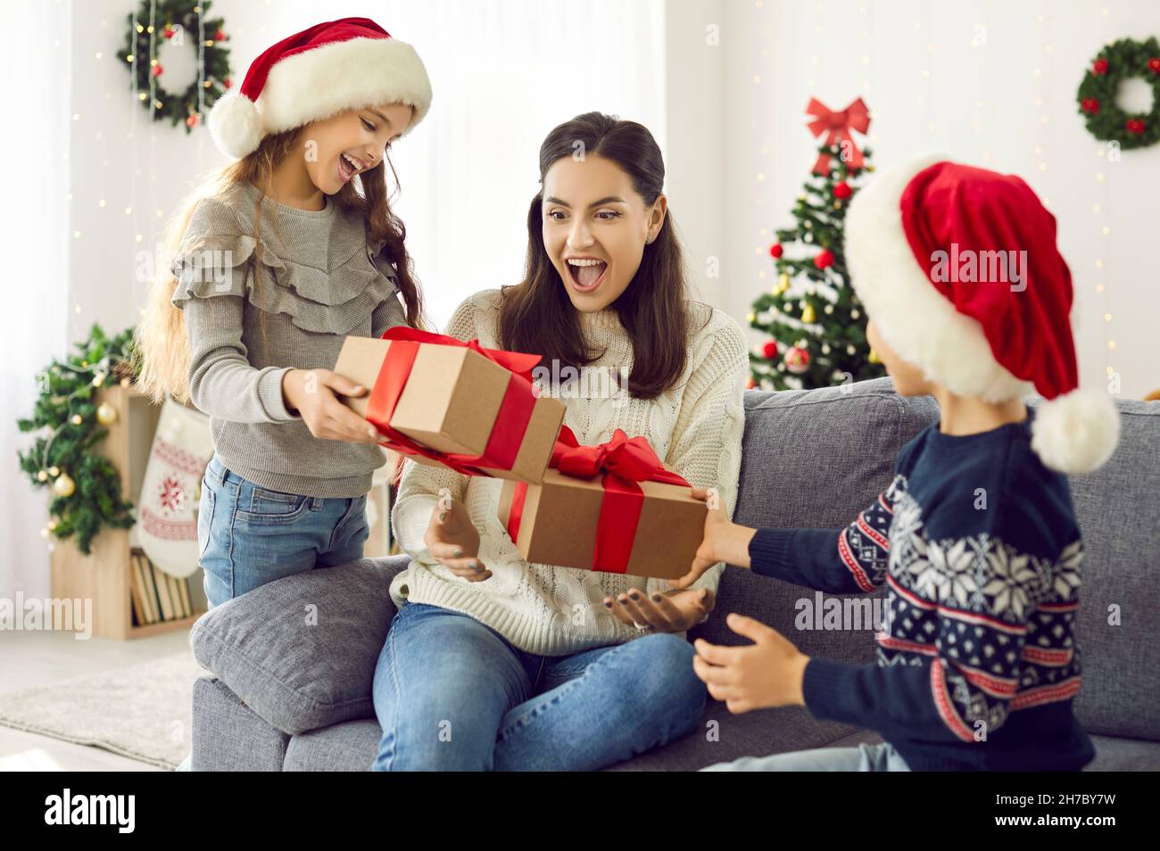 Kleine Tochter und Sohn bereiten ihrer Mutter am Weihnachtstag eine Weihnachtsüberraschung vor Stockfoto