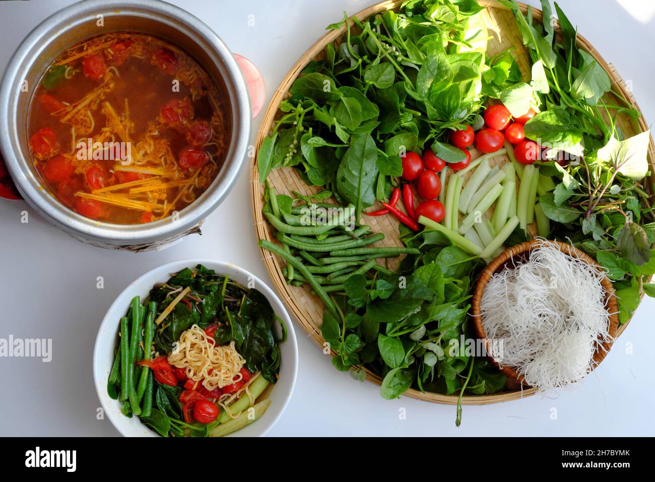 Draufsicht Vietnamesisch veganes Essen, grünes Gemüse Hotpot aus Tomaten, Sojaprotein, Chilisatte, Amaranth, Pfefferlunder, Brötchen, Spinat, gesund Stockfoto