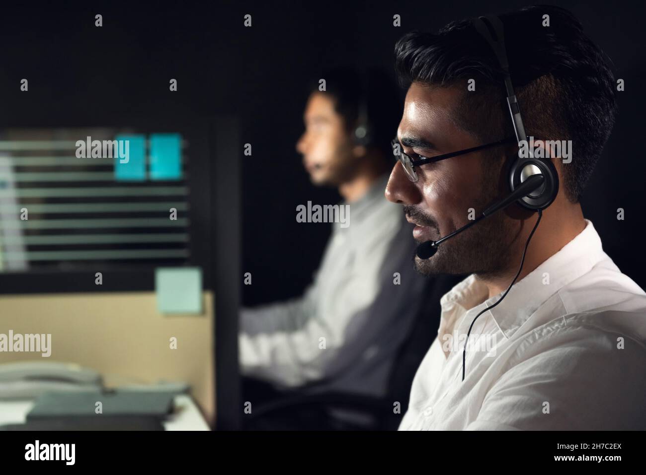 Asiatischer Geschäftsmann, der Nachtschicht im Callcenter-Büro mit einem Kollegen arbeitet Stockfoto