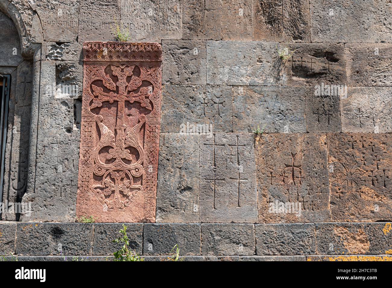 Wand einer alten mittelalterlichen armenischen Kirche mit geschnitzten Kreuzen und anderen christlichen Attributen als Hintergrund Stockfoto