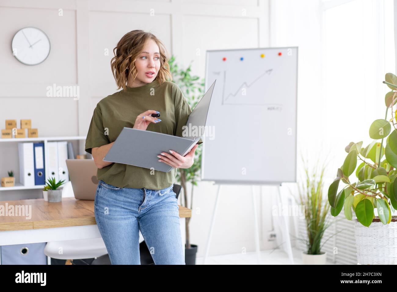Geschäftsfrau hält Ordner für Papier schreiben Marker denken träumen neben Bürotisch stehen. Business Person femal ypoung Erwachsenen kaukasisch auf Modus Stockfoto