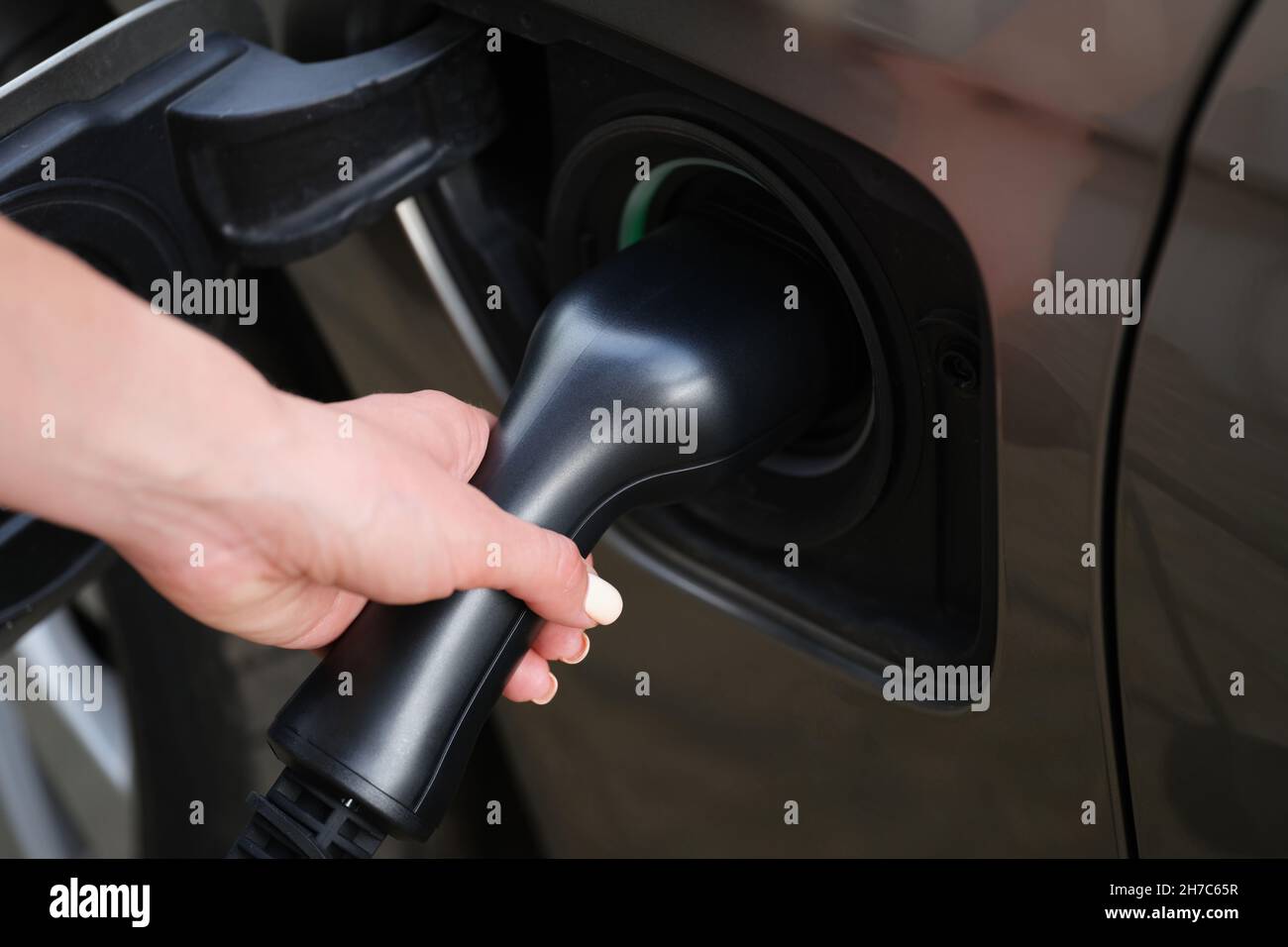 Frau setzte eine Kraftstoffdüse auf die Tankstelle, um das Auto mit Diesel zu betanken Stockfoto