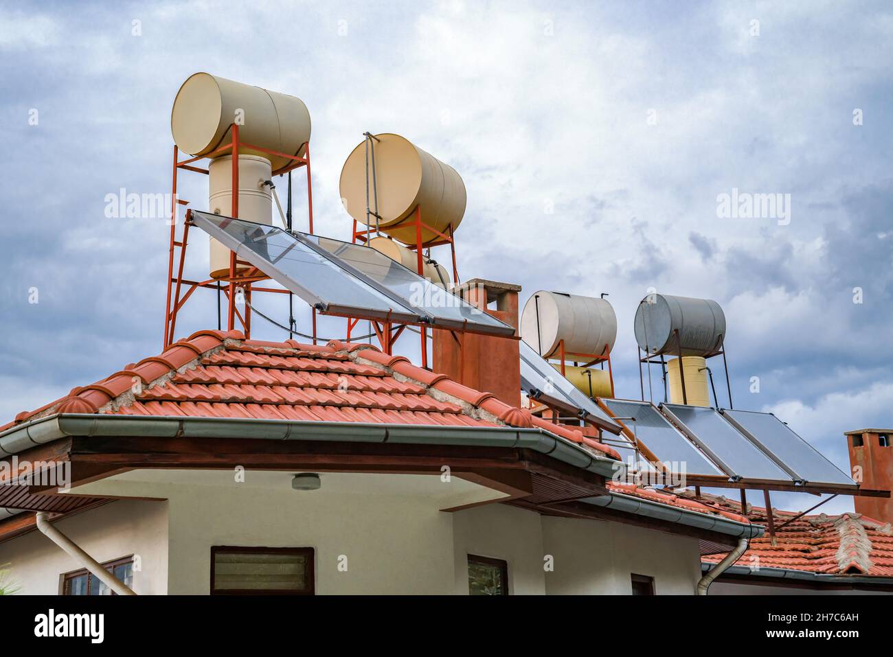 Konzept Umwelt von Freundlichkeit und Solarenergie. Wasserfässer, die durch Solarbatterien auf dem Dach des Hauses beheizt werden. Stockfoto