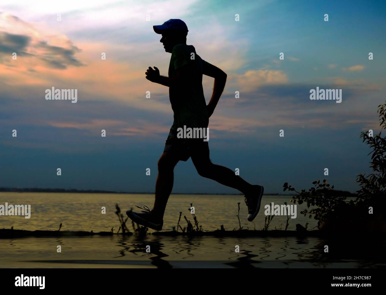 Silhouette des Mannes, der auf dem Hintergrund des Sonnenuntergangs läuft Stockfoto