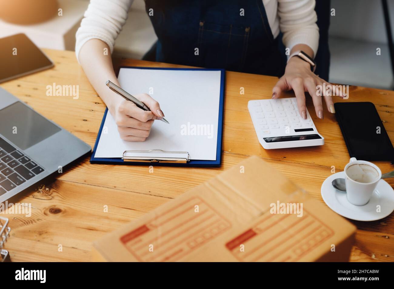 Unternehmer Besitzer mit Stift Punkt Notiz Laptop und Rechner Überprüfung Online-Kauf Bestellung zur Vorbereitung Pack Produkt Box. Verpacken von Waren für Stockfoto