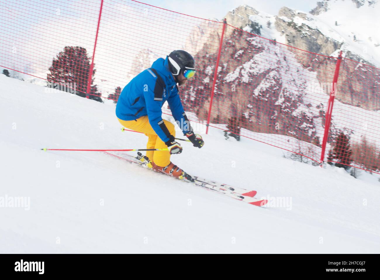 Männlicher Skifahrer in blauen und gelben Kleidern am Hang mit Berge im Hintergrund bei Cortina d'Ampezzo Col Gallina Sella Ronda Skigebiet Dolomi Stockfoto